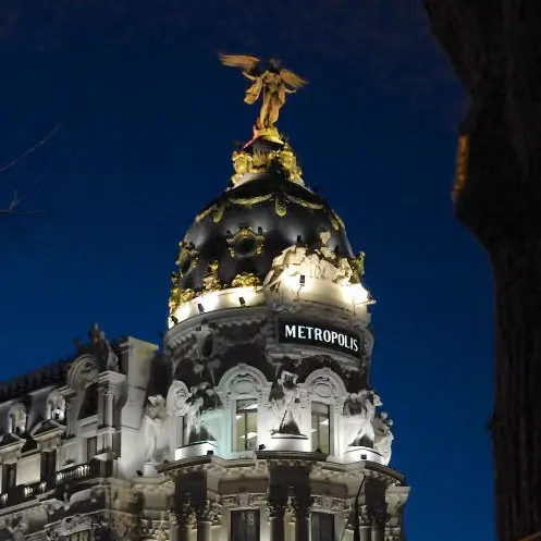 edificio metrópoli de Madrid en la intersección de Gran Vía y Alcalá, es de noche y la iluminación hace resaltar la belleza de la cúpula y el ángel que corona el edificio